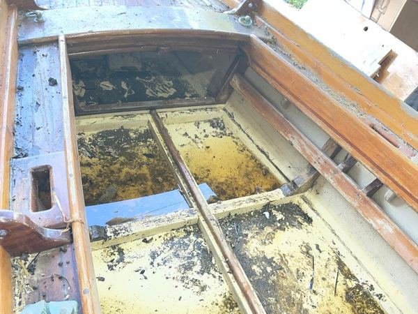 Interno di una barca classica in legno con ristagni d'acqua, fanghiglia e fondo annerito