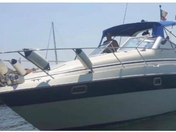 Cruiser cabinato con fascia scafo scura e gelcoat segnato dagli anni