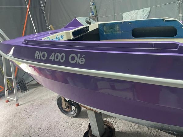 La stessa barca riverniciata in viola e bianco lucido, con il nome rifatto sulla fiancata